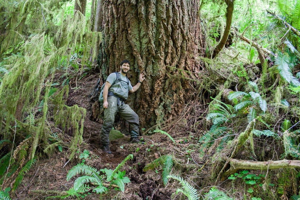 Conrad Gowell leaning against tree in forest