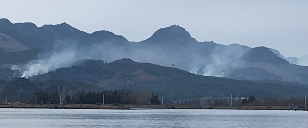 Mountains with smoke trailing from clear cutting